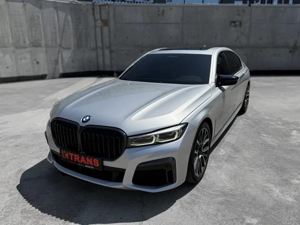 Silver 2020 BMW 740l with a KTRANS plate on a concrete parking garage roof