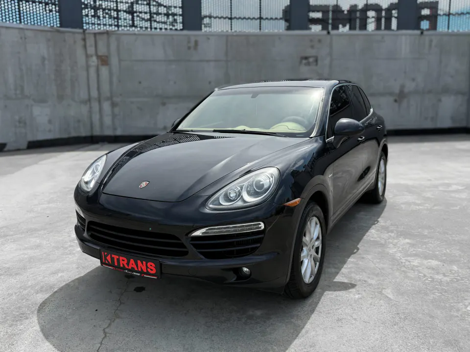 Black 2013 Porsche Cayenne with a KTRANS plate on a concrete parking garage roof